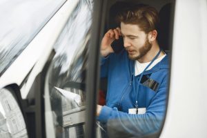 plombier au téléphone dans sa voiture