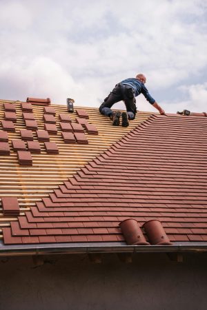 couvreur pose des tuiles sur le toit d'une maison