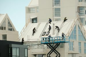 plusieurs couvreurs qui travaillent sur un toit de bâtiment